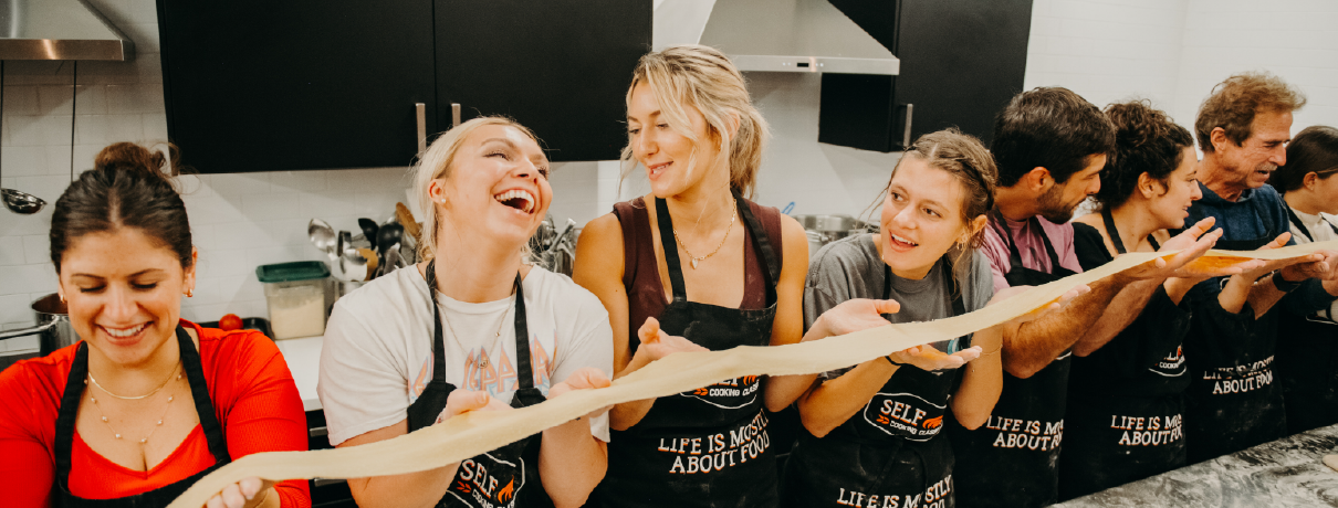 Participants enjoying a hands-on cooking class in Boston, learning to make Italian dishes together at Selfup